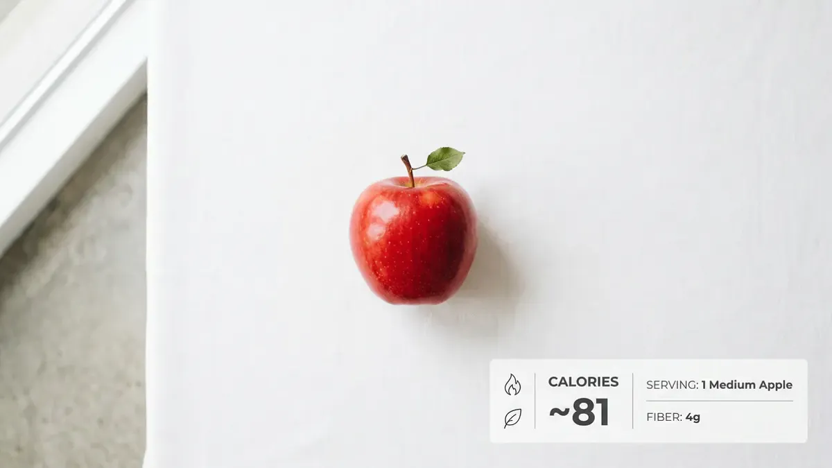 Verse groene en rode appels op een houten snijplank met een meetlint, als symbool voor calorieën bijhouden